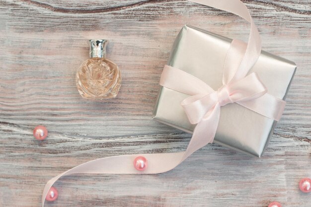 Gift box in silver paper with a pink ribbon and perfume