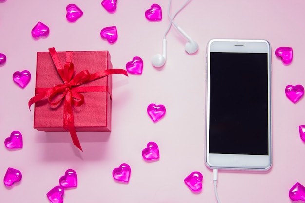 분홍색 배경에 선물 상자와 스마트폰 여자의 날 선물 사무실 책상