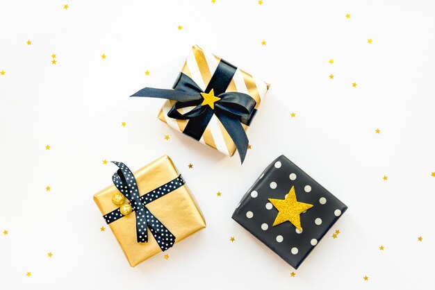 Gift box over star shaped golden sequins on a white background.