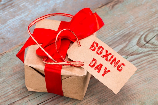 Подарочная коробка и бирка с текстом: день бокса, на деревянном фоне.