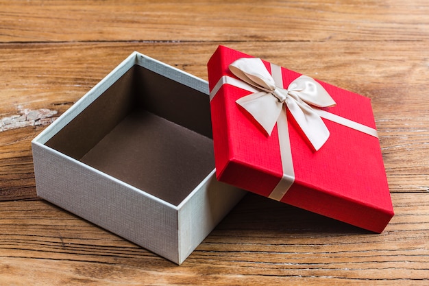 Gift box tied red ribbon with small red hearts printed on it. On old wooden background.