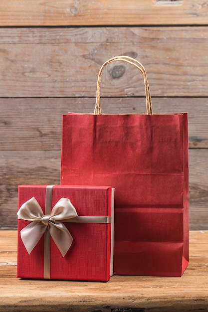 Gift box tied red ribbon with small red hearts printed on it. On old wooden background.