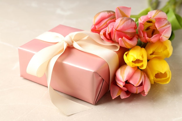 Gift box and tulips on light background