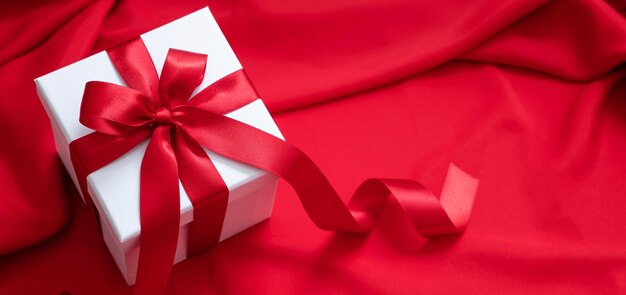 Gift box white with red ribbon on satin background christmas\
valentine day present decoration