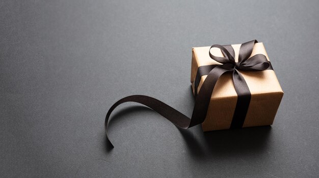 Gift box with black ribbon against black background Black Friday concept