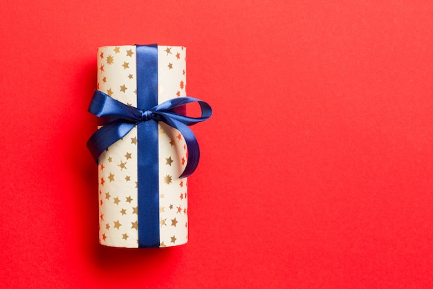 Gift box with blue bow for Christmas or New Year day on red background