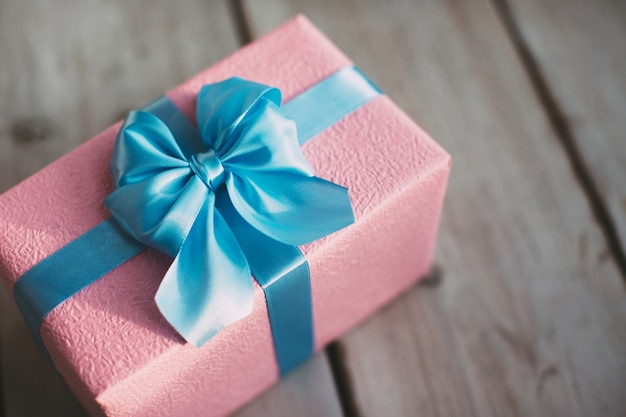 Gift box with blue bow on wooden background