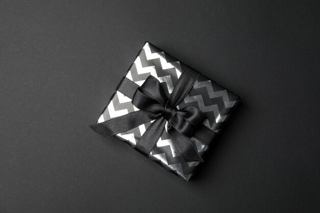 Gift box with bow on black space. Black Friday sale