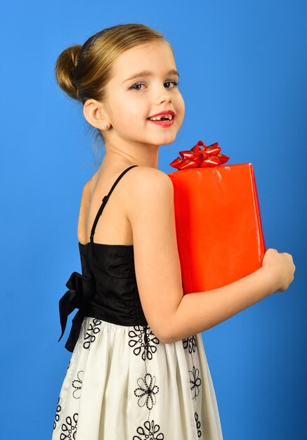 Gift box with bow in the childrens hands on blue background
