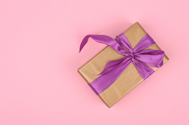 Gift box with bow on pink paper background. Greeting card for birthday, mothers day or valentines day.