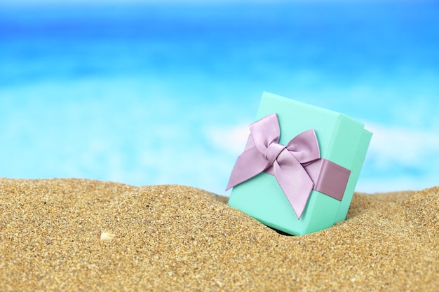 Gift box with bow on the sand