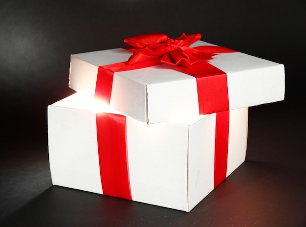 Gift box with bright light on it on dark grey background