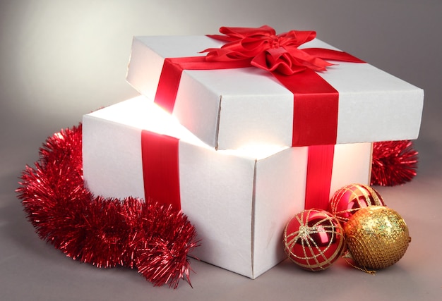 Gift box with bright light on it on grey background