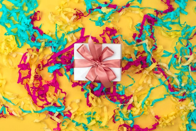 Gift box with colored streamers bright yellow background