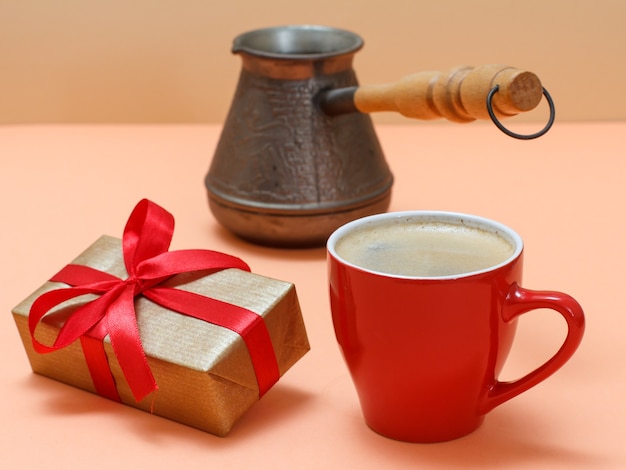 Gift box with cup of coffee on a beige background.