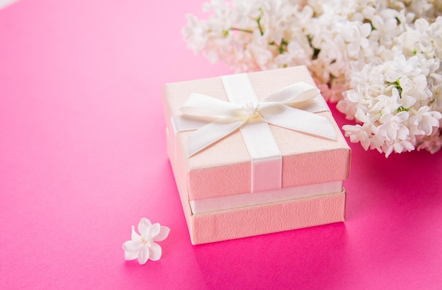 Gift box with flowers on pink background