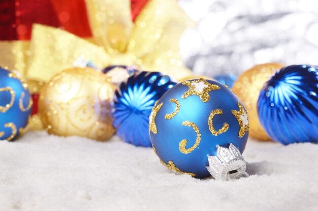 Gift box with golden and blue christmas balls in the snow closeup