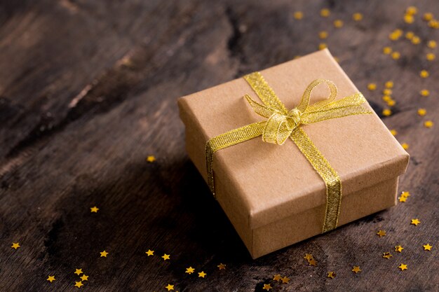 Gift box with golden bow on wooden table