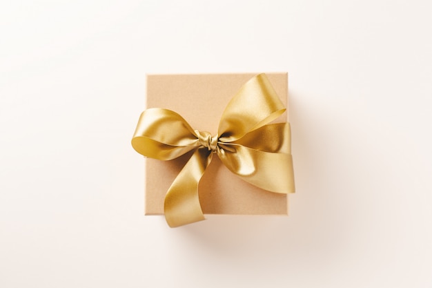 Gift box with golden ribbon on bright 