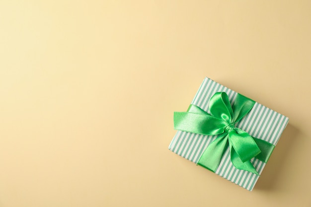 Gift box with green ribbon on color background, top view and space for text