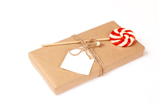 gift box with lollipop and blank tag close up on white background