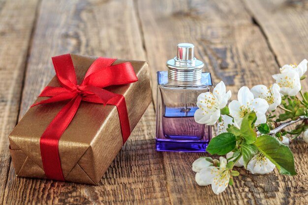 Foto confezione regalo con profumo e ramo di bellissimi fiori di gelsomino sullo sfondo di legno