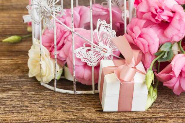 Gift box with pink bow and bunch of fresh roses and eustoma flowers