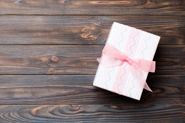 Gift box with pink bow on dark wooden table