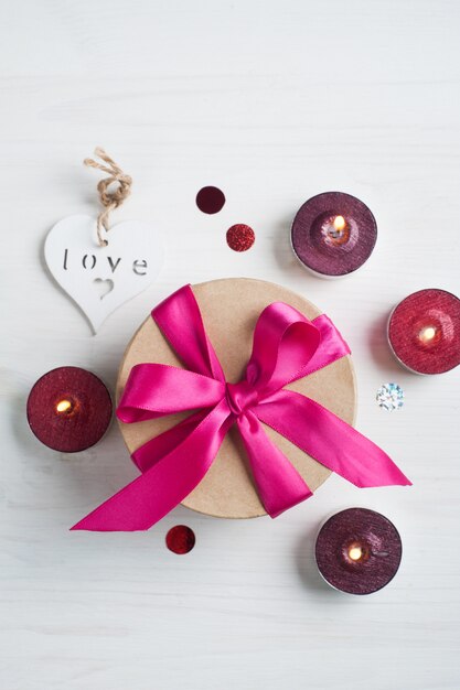 Gift box with pink bow and lit candles