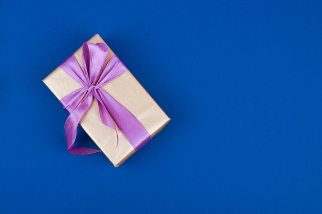 Gift box with purple ribbon isolated on blue space. Top view