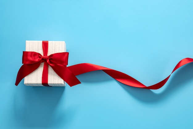 Photo gift box with red bow on a blue background .