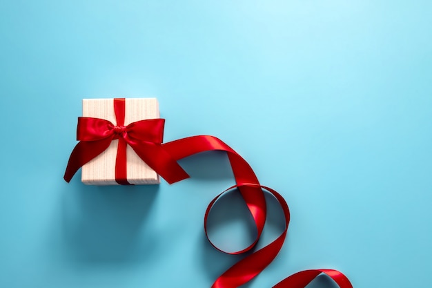 Photo gift box with red bow on a blue background .