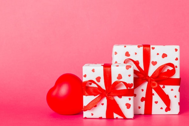 Подарочная коробка с красным луком и красным сердцем на цветном фоне Перспективный вид