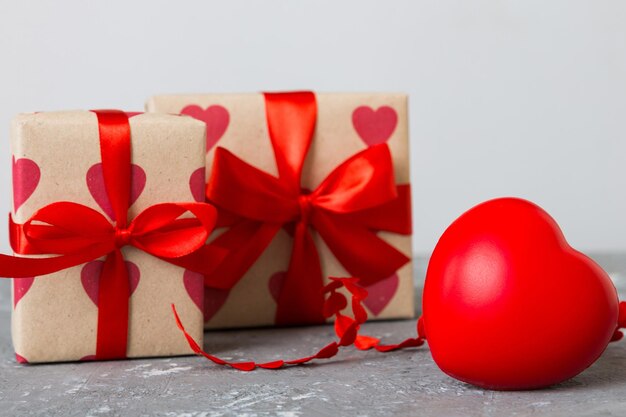 gift box with red bow and red heart on colored background Perspective view Flat lay