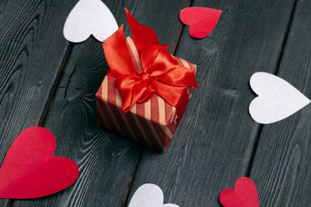 Gift box with red bow ribbon and  paper hearts for Valentines day