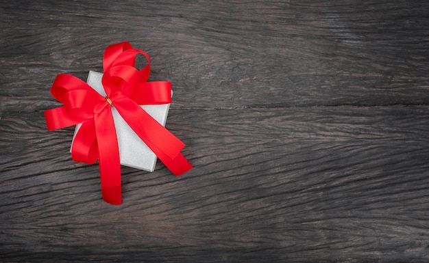 The Gift box with the red bow on wood space