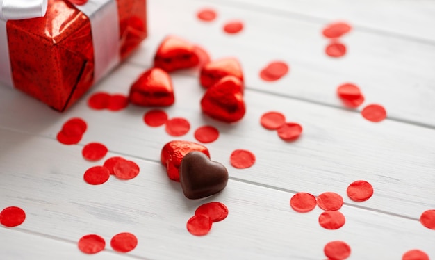 Confezione regalo con una forma di cuore rosso chokolate su sfondo di san valentino in legno bianco banner biglietto di auguri