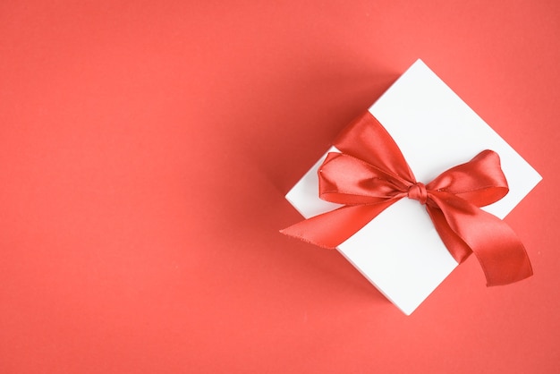 Gift box with red ribbon bow on red.