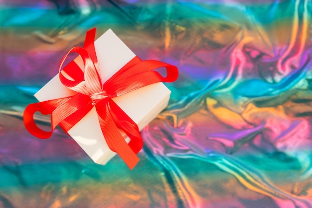 gift box with red ribbon, glittery colorful background.Magical Christmas present box wrapped with