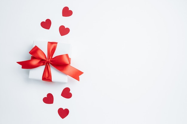 Confezione regalo con nastro rosso e cuori su sfondo bianco san valentino