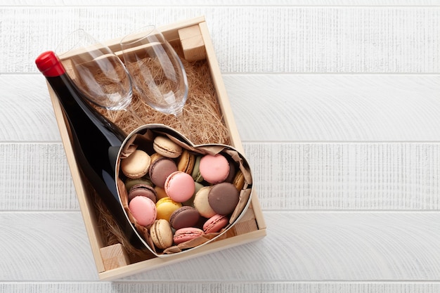 Gift box with red wine bottle and macaroons Top view flat lay with copy space