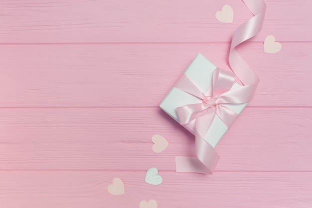 Gift box with ribbon near heart shapes