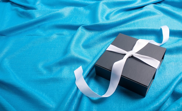 Gift box with silver ribbon blue background