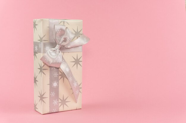 Gift box with stars and gray ribbon on a pink background with copy space