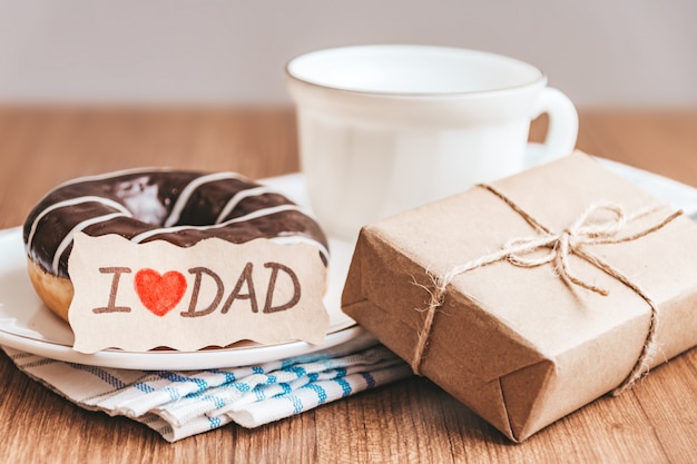 Foto confezione regalo con etichetta, tazza di caffè o ciambella al cioccolato e tè