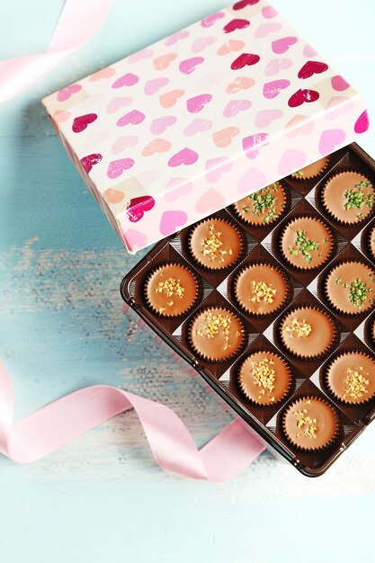 Gift box with tasty chocolate candies on wooden table