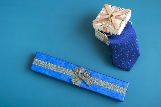 Gift box with a tie on a turquoise background. Holiday gifts closeup with copy space