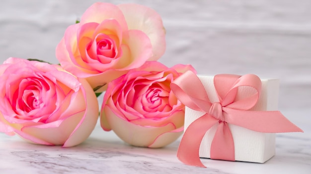 Foto scatola regalo con fiocco di nastro legato rose rosa su sfondo rosa regalo di biglietto di auguri per la primavera