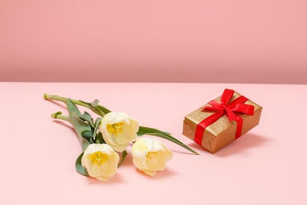 Gift box with tulip flowers on a pink background