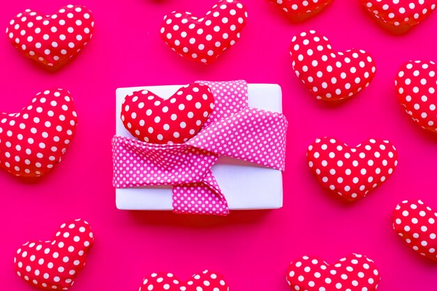 Gift box with Valentine's hearts on red background. 